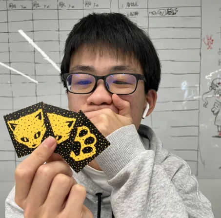 A person holding up three cards in one hand while covering their mouth with the other.